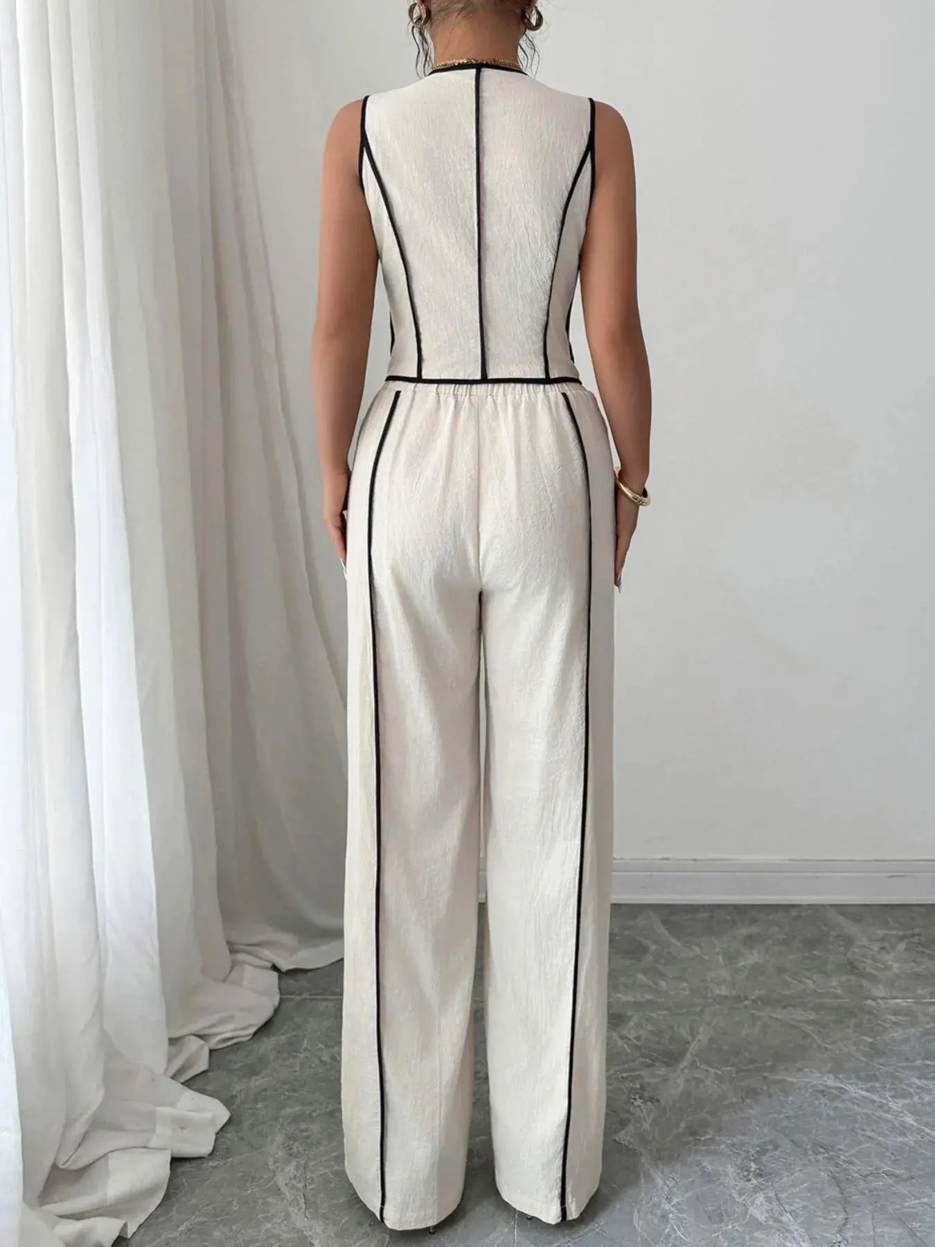 Elevate your everyday wardrobe with this contrast trim V-neck vest and pants set—a polished two-piece ensemble that blends tailored structure with relaxed ease. The sleeveless vest features a deep V-neckline and crisp contrast piping, offering a modern take on classic suiting. Buttoned detailing adds a refined touch, making it perfect for both work and weekend wear.