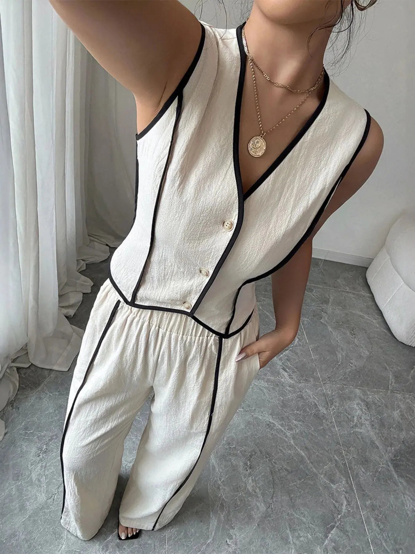Elevate your everyday wardrobe with this contrast trim V-neck vest and pants set—a polished two-piece ensemble that blends tailored structure with relaxed ease. The sleeveless vest features a deep V-neckline and crisp contrast piping, offering a modern take on classic suiting. Buttoned detailing adds a refined touch, making it perfect for both work and weekend wear.
