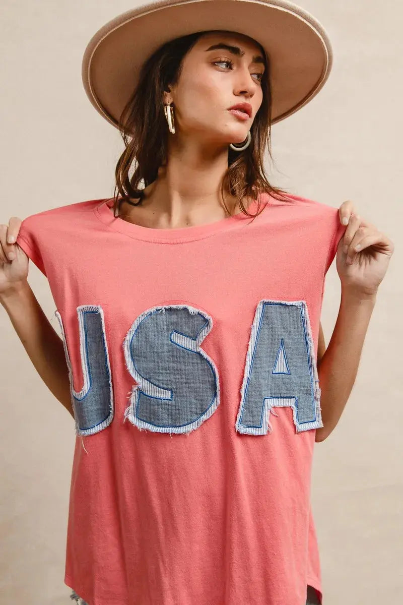 This fashion USA graphic t-shirt features a vibrant coral pink base with bold denim-style USA lettering across the chest. Made from soft cotton blend fabric for ultimate comfort and breathability. The relaxed oversized fit provides a casual, effortless look perfect for everyday wear. The vintage-inspired patriotic design makes it ideal for summer festivals, casual outings, or showing American pride. The round neckline and loose silhouette offer versatile styling options for pairing with jeans, shorts, etc.
