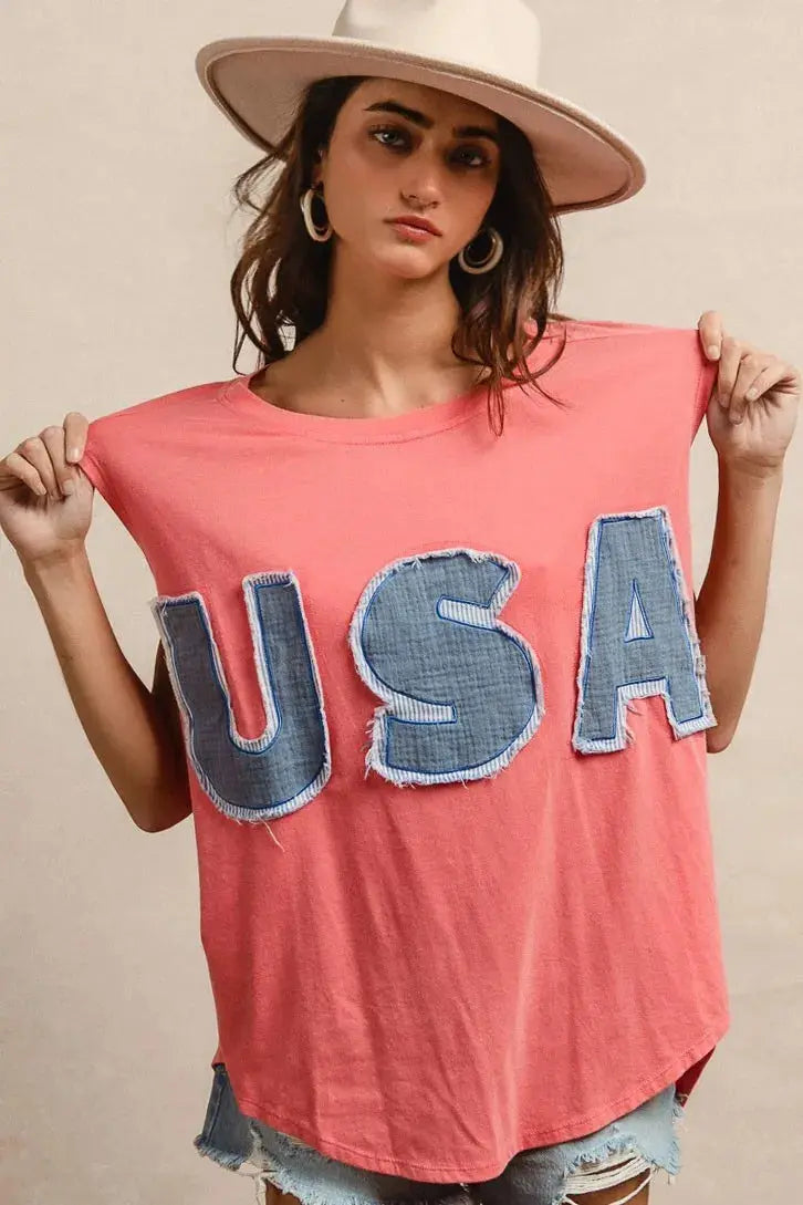 This fashion USA graphic t-shirt features a vibrant coral pink base with bold denim-style USA lettering across the chest. Made from soft cotton blend fabric for ultimate comfort and breathability. The relaxed oversized fit provides a casual, effortless look perfect for everyday wear. The vintage-inspired patriotic design makes it ideal for summer festivals, casual outings, or showing American pride. The round neckline and loose silhouette offer versatile styling options for pairing with jeans, shorts, etc.