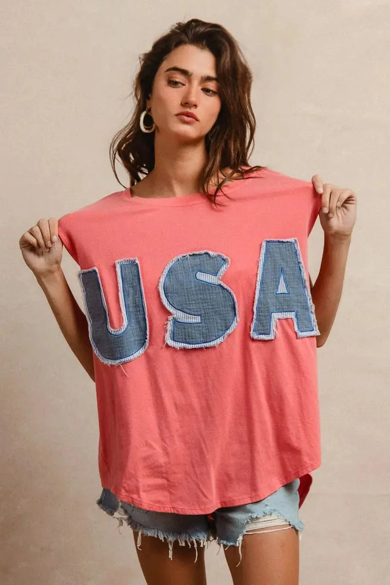 This fashion USA graphic t-shirt features a vibrant coral pink base with bold denim-style USA lettering across the chest. Made from soft cotton blend fabric for ultimate comfort and breathability. The relaxed oversized fit provides a casual, effortless look perfect for everyday wear. The vintage-inspired patriotic design makes it ideal for summer festivals, casual outings, or showing American pride. The round neckline and loose silhouette offer versatile styling options for pairing with jeans, shorts, etc.