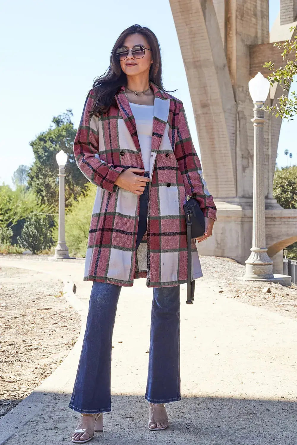 Wrap yourself in cozy charm with this Pink Plaid Button-Up Coat—a statement layer that blends warmth with playful sophistication. Designed in a soft checkered weave of blush, ivory, and brown, this midweight coat features a relaxed fit that’s perfect for layering over your everyday essentials. Classic button-front detailing and side pockets offer practicality, while the longline silhouette adds a modern, polished finish. Whether you're strolling downtown or escaping to a weekend cabin, this piece brings tex