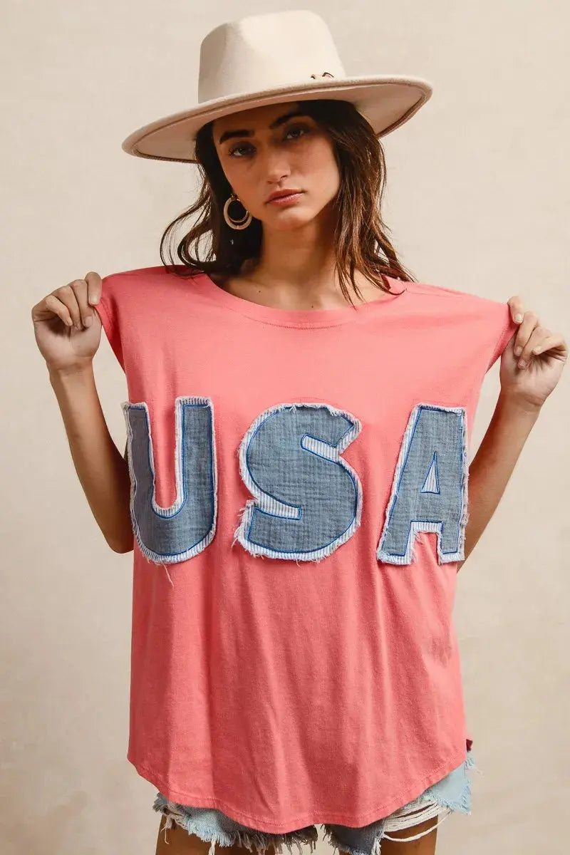 This fashion USA graphic t-shirt features a vibrant coral pink base with bold denim-style USA lettering across the chest. Made from soft cotton blend fabric for ultimate comfort and breathability. The relaxed oversized fit provides a casual, effortless look perfect for everyday wear. The vintage-inspired patriotic design makes it ideal for summer festivals, casual outings, or showing American pride. The round neckline and loose silhouette offer versatile styling options for pairing with jeans, shorts, etc.