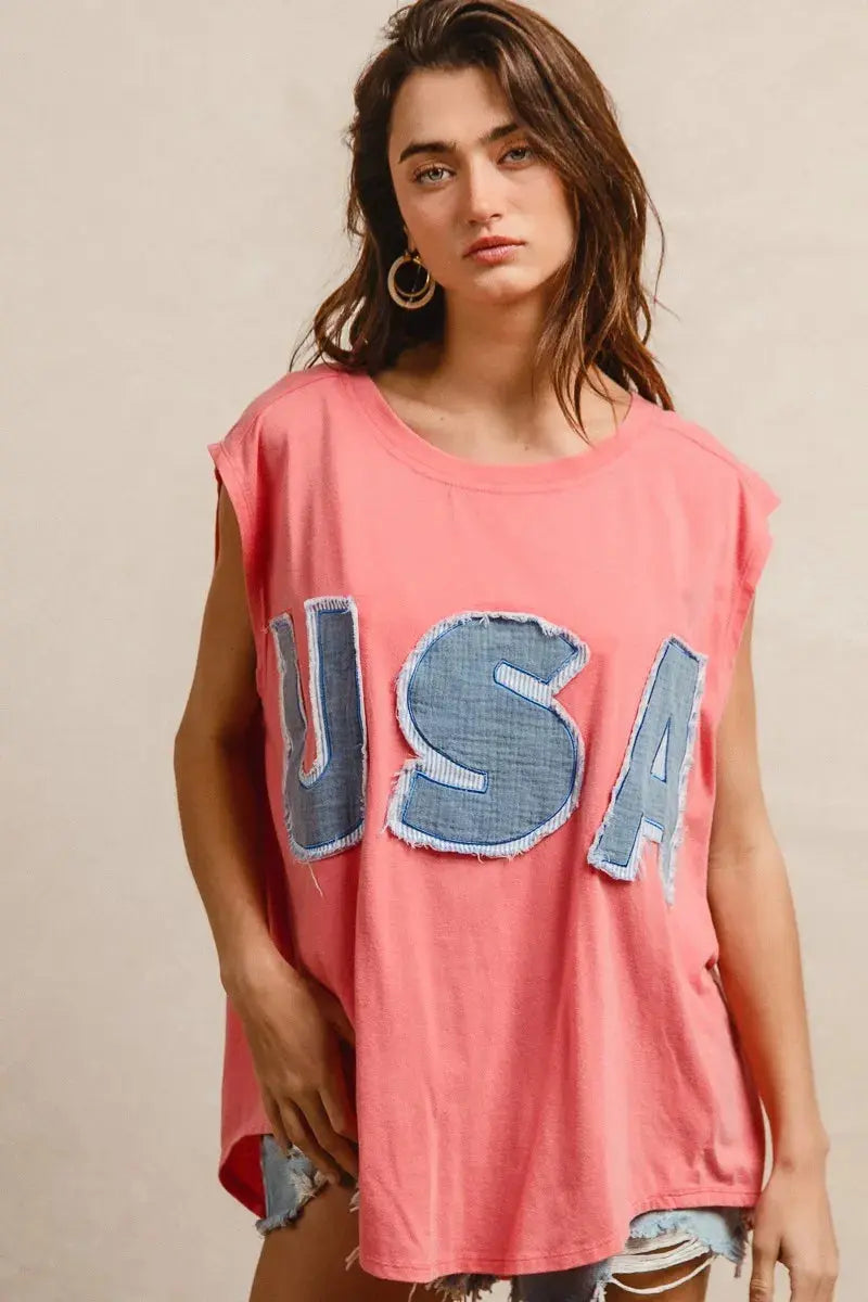This fashion USA graphic t-shirt features a vibrant coral pink base with bold denim-style USA lettering across the chest. Made from soft cotton blend fabric for ultimate comfort and breathability. The relaxed oversized fit provides a casual, effortless look perfect for everyday wear. The vintage-inspired patriotic design makes it ideal for summer festivals, casual outings, or showing American pride. The round neckline and loose silhouette offer versatile styling options for pairing with jeans, shorts, etc.
