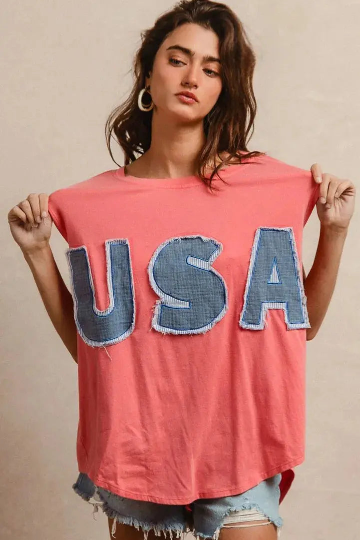 This fashion USA graphic t-shirt features a vibrant coral pink base with bold denim-style USA lettering across the chest. Made from soft cotton blend fabric for ultimate comfort and breathability. The relaxed oversized fit provides a casual, effortless look perfect for everyday wear. The vintage-inspired patriotic design makes it ideal for summer festivals, casual outings, or showing American pride. The round neckline and loose silhouette offer versatile styling options for pairing with jeans, shorts, etc.