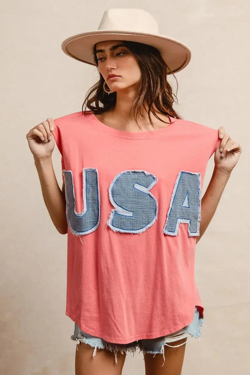 This fashion USA graphic t-shirt features a vibrant coral pink base with bold denim-style USA lettering across the chest. Made from soft cotton blend fabric for ultimate comfort and breathability. The relaxed oversized fit provides a casual, effortless look perfect for everyday wear. The vintage-inspired patriotic design makes it ideal for summer festivals, casual outings, or showing American pride. The round neckline and loose silhouette offer versatile styling options for pairing with jeans, shorts, etc.