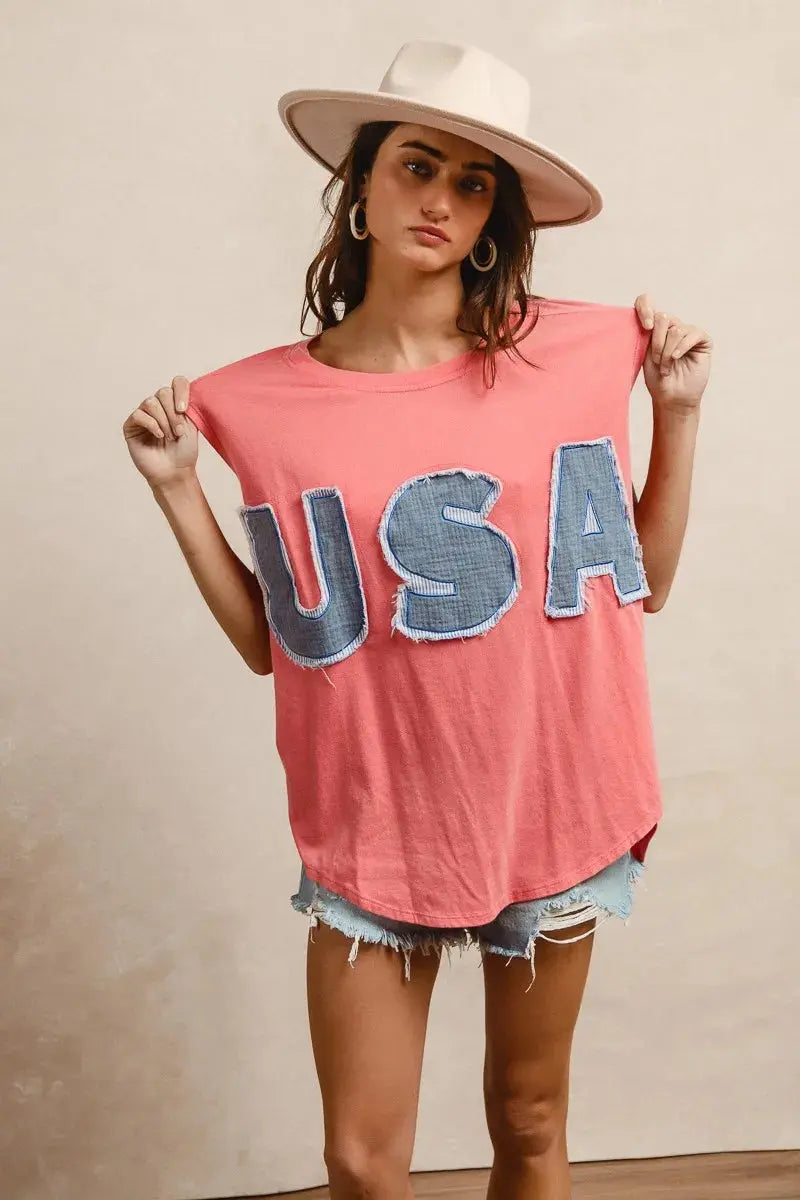 This fashion USA graphic t-shirt features a vibrant coral pink base with bold denim-style USA lettering across the chest. Made from soft cotton blend fabric for ultimate comfort and breathability. The relaxed oversized fit provides a casual, effortless look perfect for everyday wear. The vintage-inspired patriotic design makes it ideal for summer festivals, casual outings, or showing American pride. The round neckline and loose silhouette offer versatile styling options for pairing with jeans, shorts, etc.