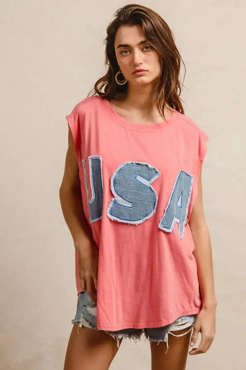 This fashion USA graphic t-shirt features a vibrant coral pink base with bold denim-style USA lettering across the chest. Made from soft cotton blend fabric for ultimate comfort and breathability. The relaxed oversized fit provides a casual, effortless look perfect for everyday wear. The vintage-inspired patriotic design makes it ideal for summer festivals, casual outings, or showing American pride. The round neckline and loose silhouette offer versatile styling options for pairing with jeans, shorts, etc.
