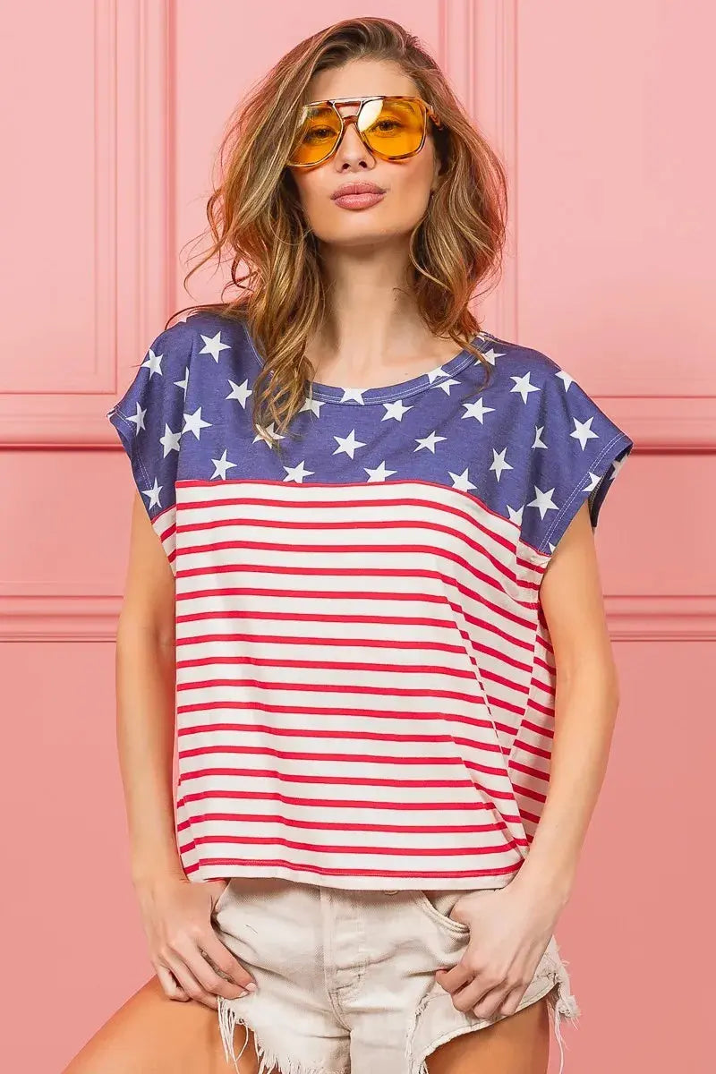 Woman wearing an American flag shirt against a pink background.