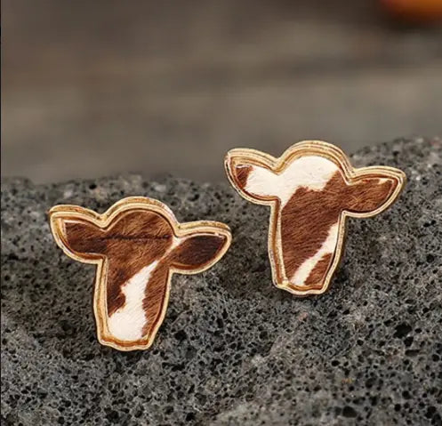 pair of bold boho cowhide stud earrings on rustic background.