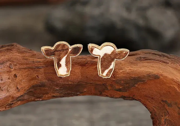 pair of bold boho cowhide stud earrings on rustic background.