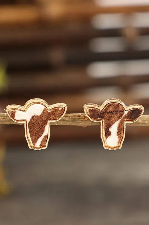 pair of bold boho cowhide stud earrings on rustic background.