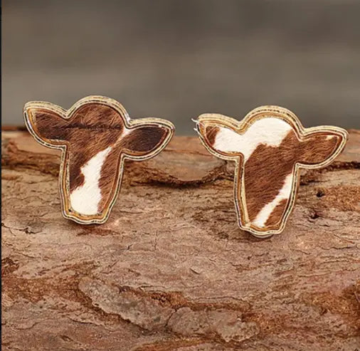 pair of bold boho cowhide stud earrings on rustic background.