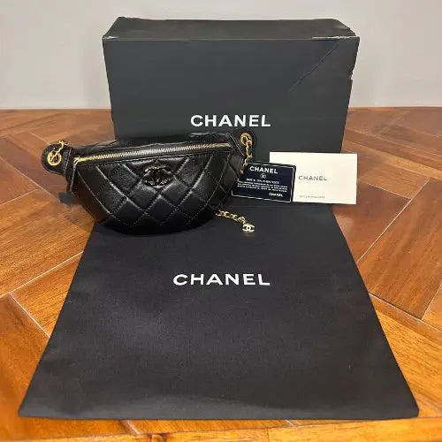 Black quilted Chanel bag with box and dust bag on a wooden surface