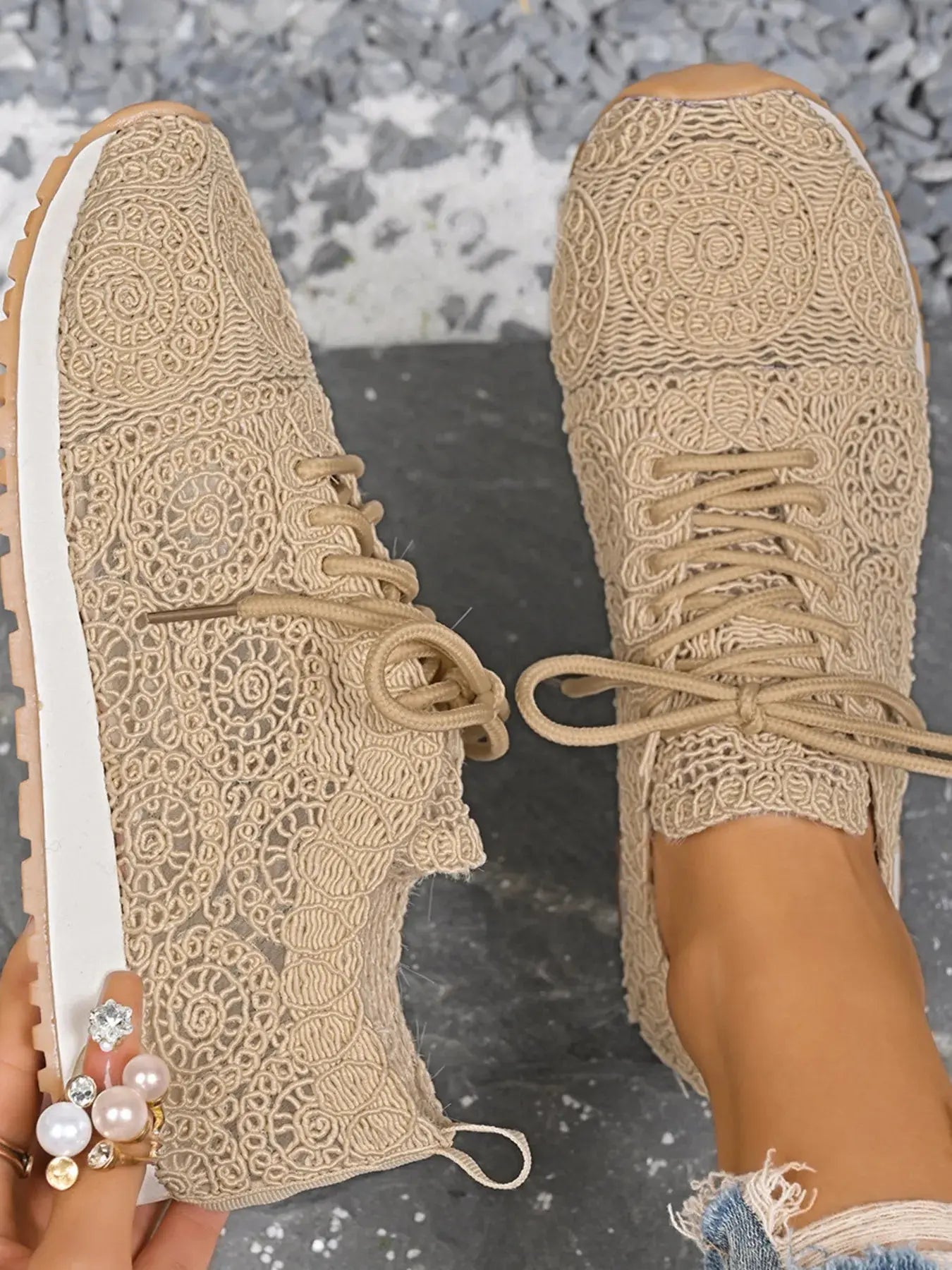 Beige lace-up sneakers worn with a textured gray surface background
