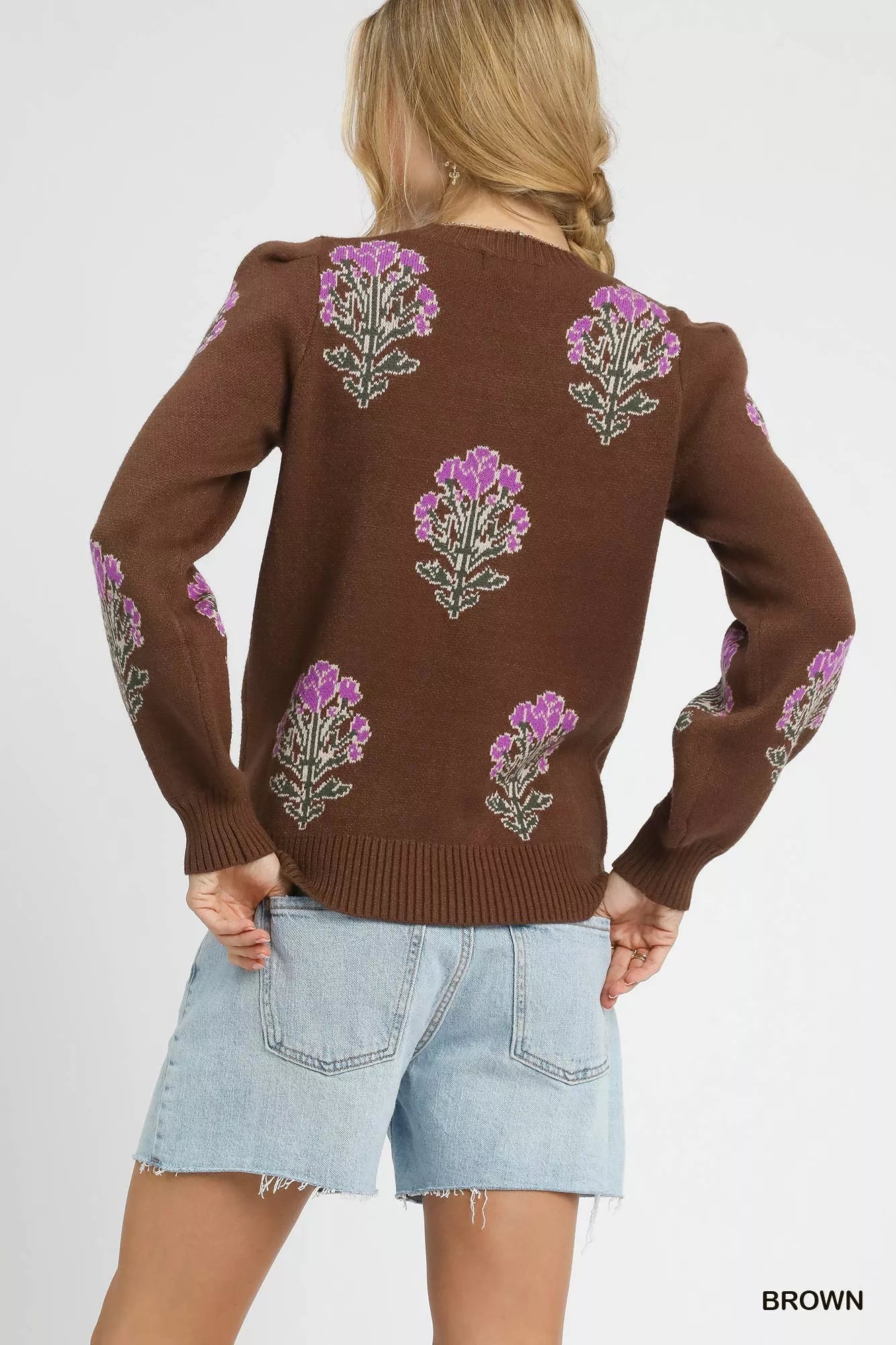Brown sweater with floral patterns worn by a person on a white background