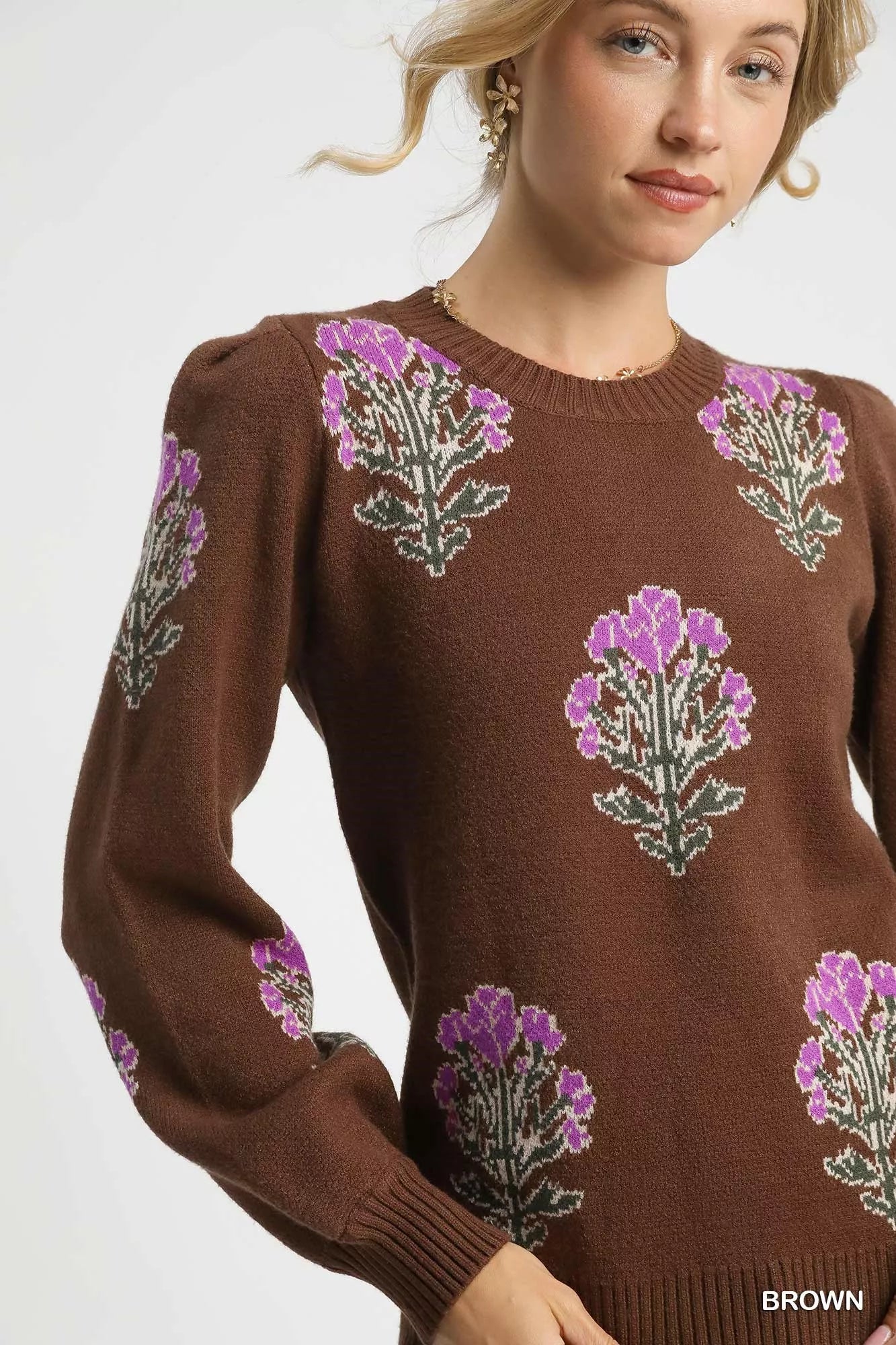 Woman wearing a brown sweater with floral patterns on a white background