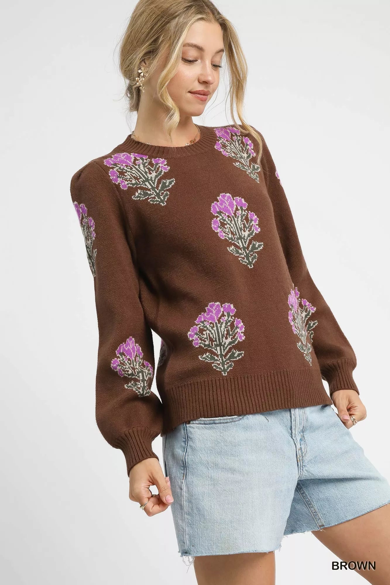 Woman wearing a brown sweater with floral patterns on a white background