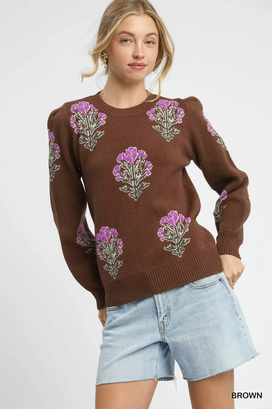 Woman wearing a brown sweater with floral patterns on a white background