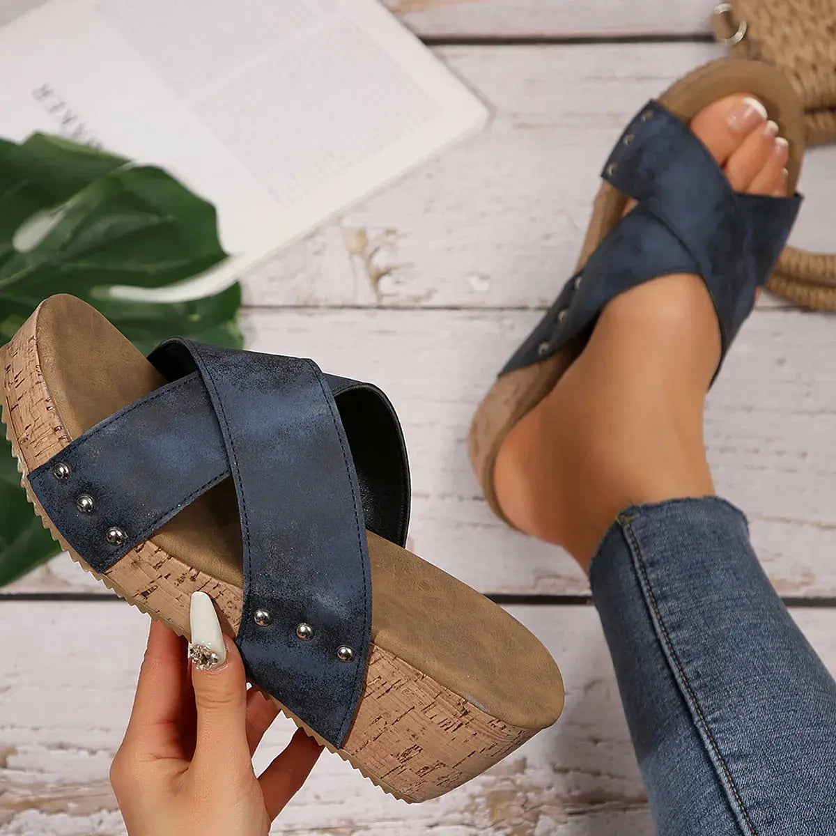 Navy sandals with cork sole worn by a person on a wooden floor.
