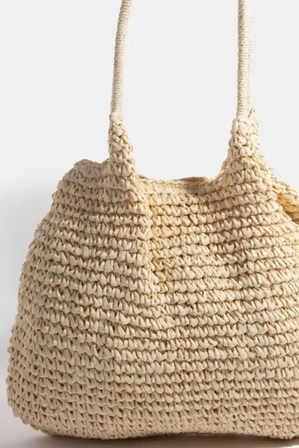 A close-up of a beige woven handbag on a light gray background.