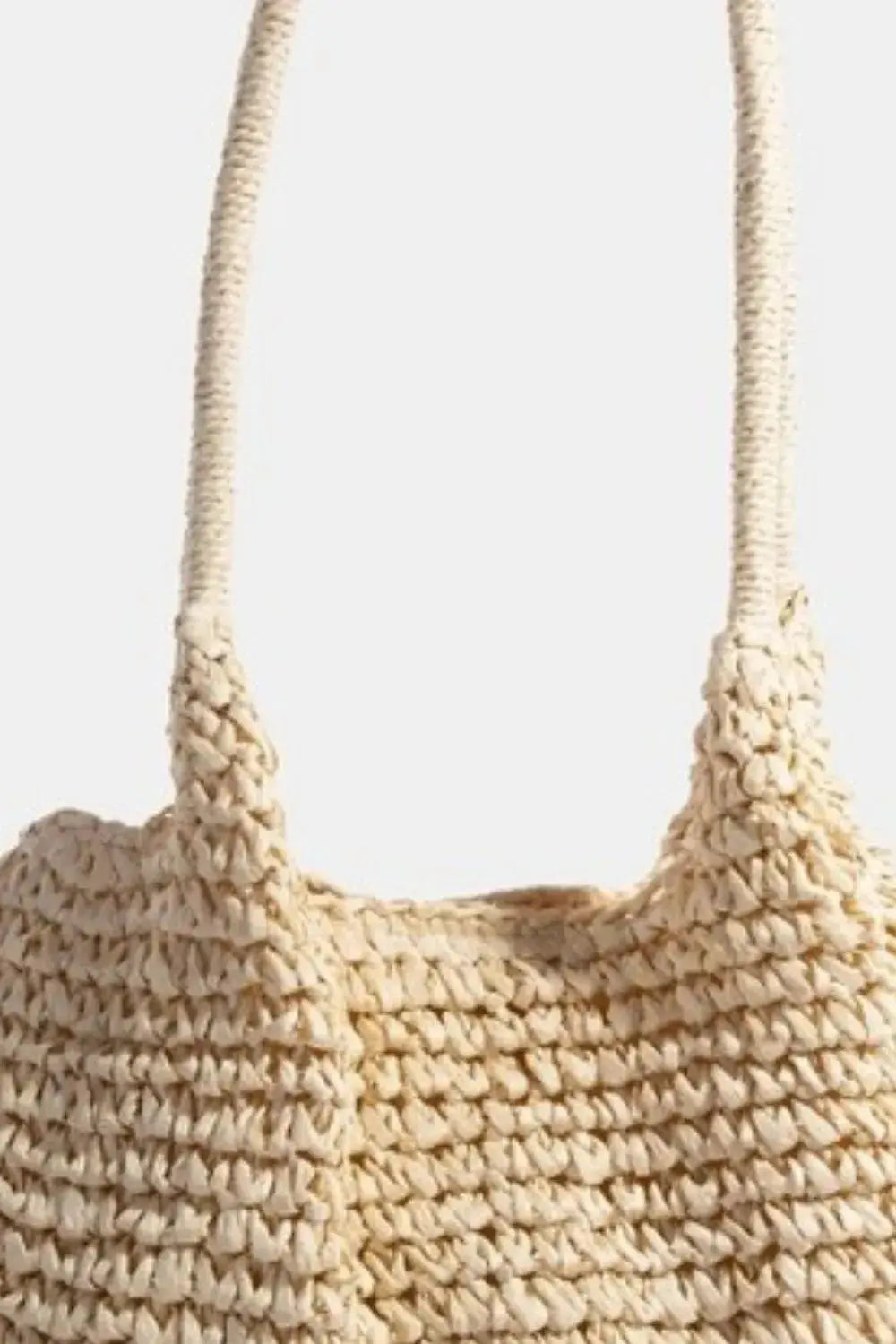 Close-up of a beige woven handbag with a handle.