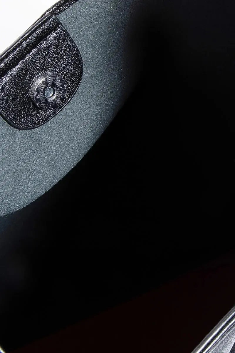 Close-up of the inside of a black faux leather bag with a metal closure.