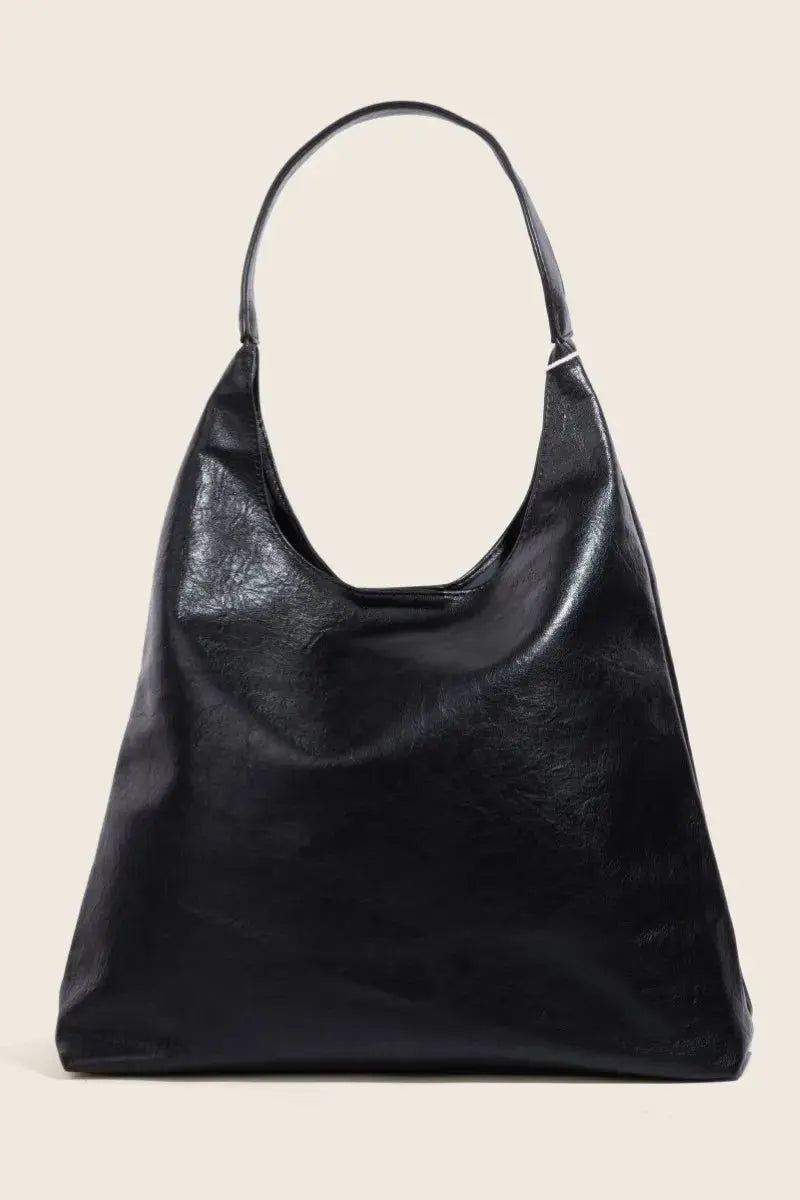 Black faux leather handbag on a beige background.