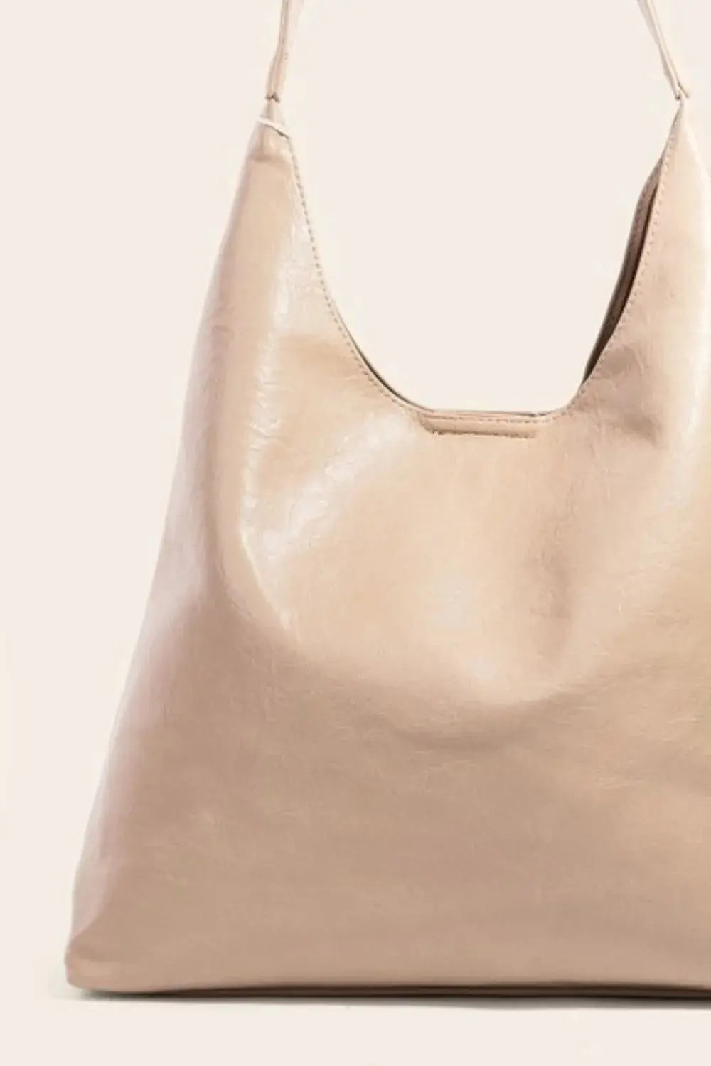 One side of a beige faux leather handbag on a light beige background.