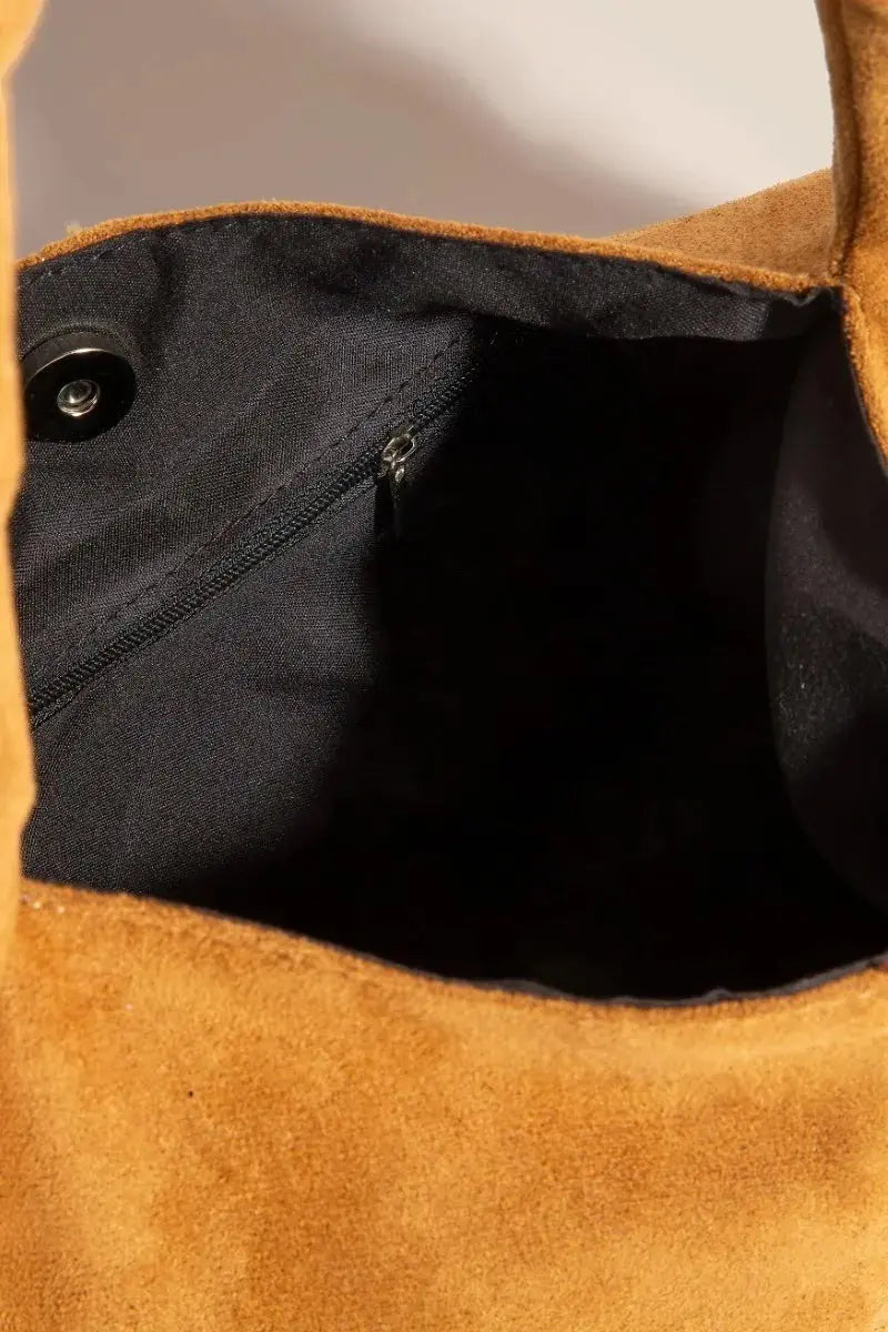 Close-up of the inside of a brown suede bag with a black interior.
