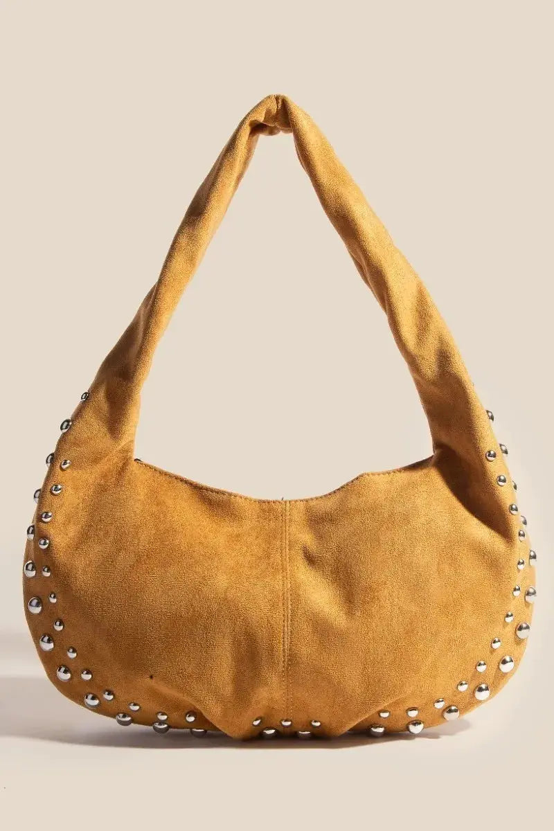 This luxurious hobo shoulder bag features buttery-soft suede leather in a rich caramel tone, adorned with edgy silver studs along the curved bottom edge. The relaxed hobo shape offers generous storage space while maintaining a sophisticated silhouette.