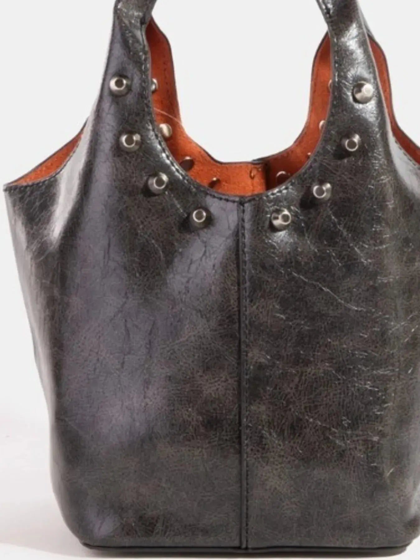Black faux leather handbag with brown interior and silver studs on a white background.
