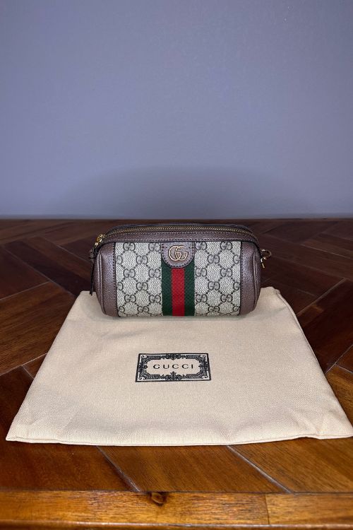 Gucci handbag on a branded Gucci pouch with a wooden floor and blue wall background