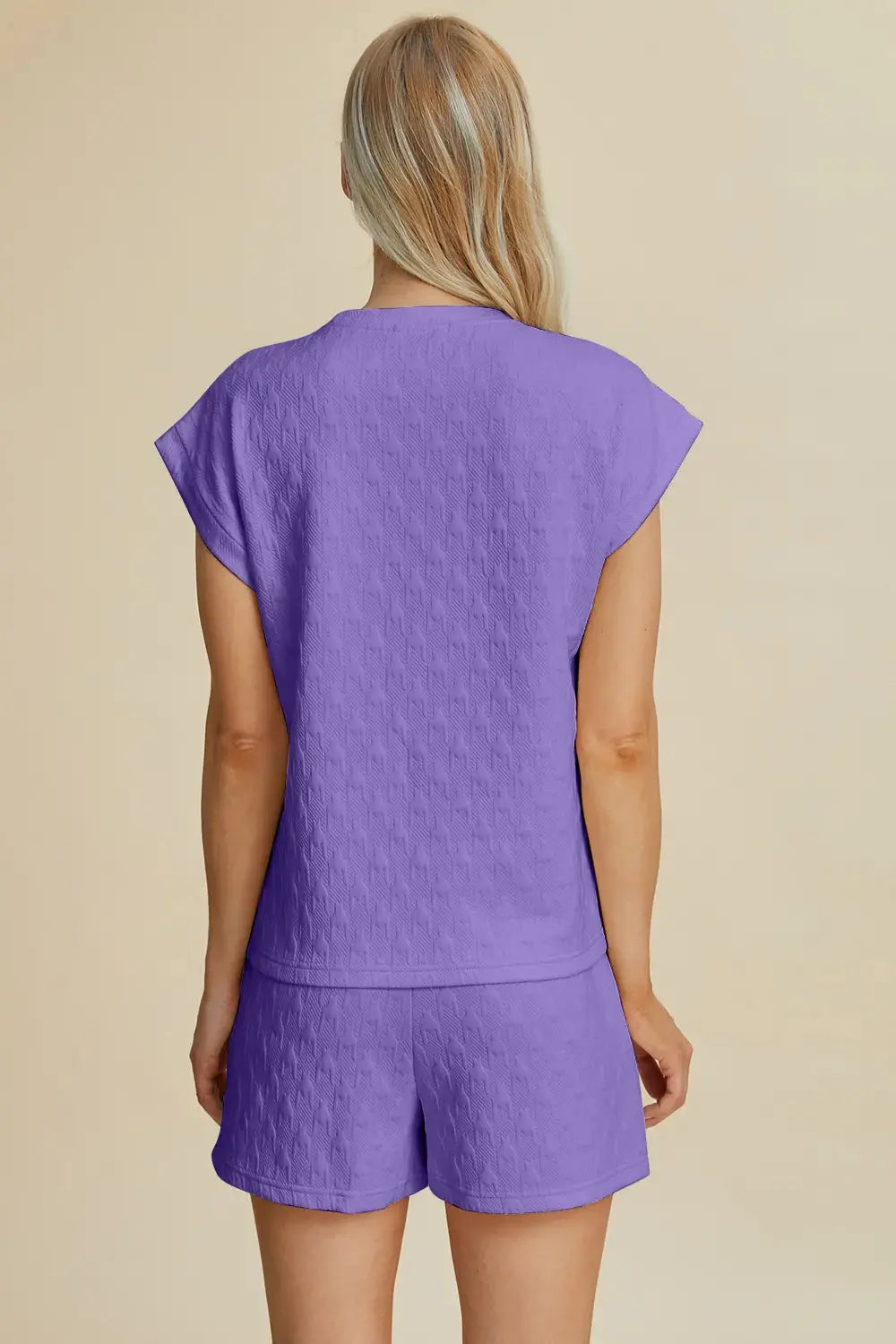 Ease meets elegance in this textured two-piece lounge set, featuring a short-sleeve top with a round neckline and functional chest pocket. The matching shorts are designed with an elastic waistband and side pockets, offering unrestricted comfort without compromising style. The soft lavender hue adds a refreshing pop to your off-duty look—perfect for warm days, staycations, or casual brunches. Whether worn as a set or styled separately, this duo brings versatility to your everyday edit.