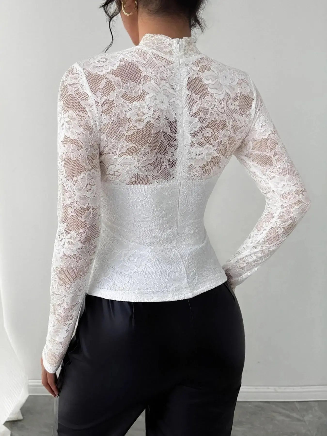Person wearing a white lace long-sleeve top against a gray background