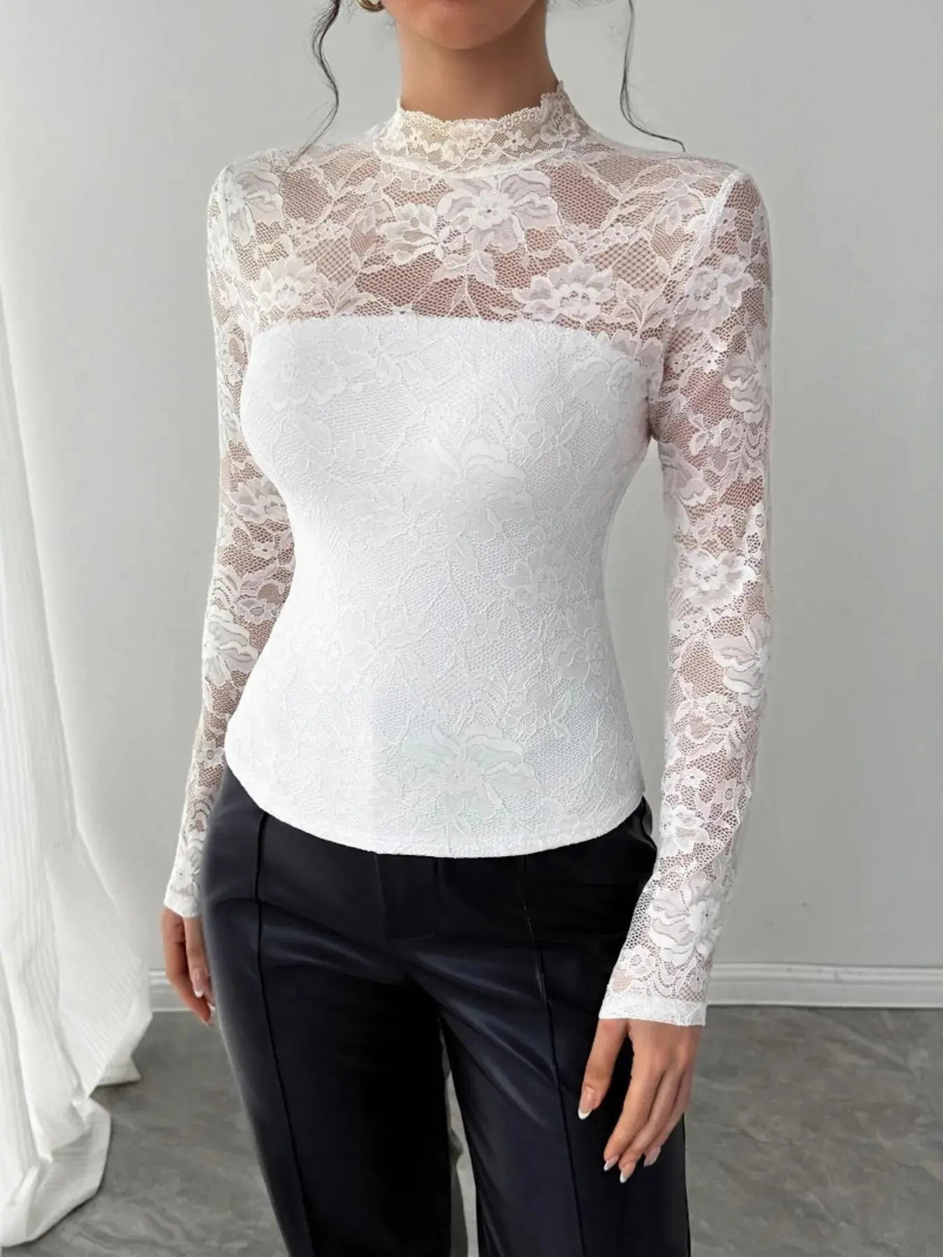 Person wearing a white lace top with long sleeves against a plain background