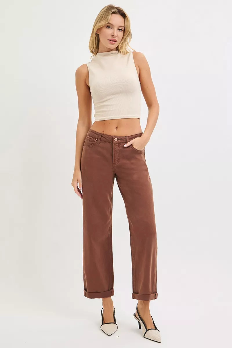Woman wearing a beige sleeveless top and brown pants on a white background