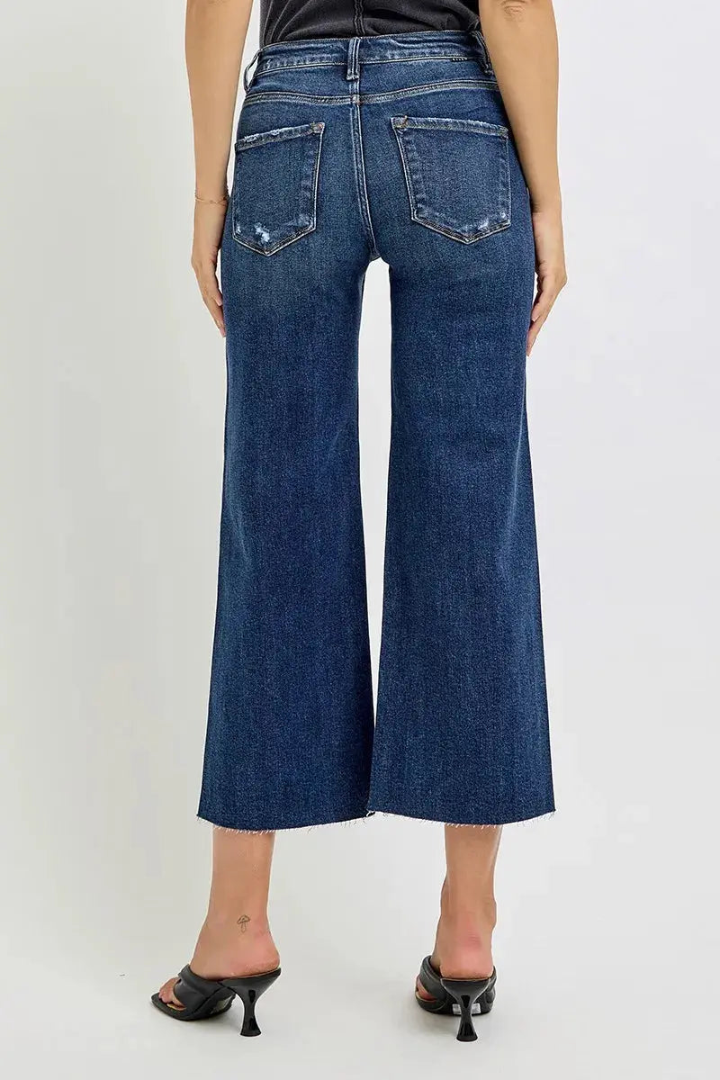 Person with their back to the camera wearing blue wide-leg jeans on a plain background.