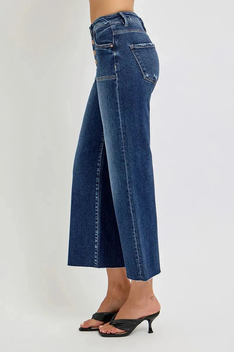 A person standing to the side wearing blue jeans on a white background.