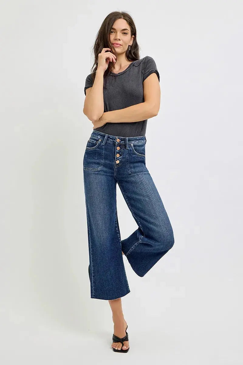 Woman wearing a dark gray t-shirt and blue jeans on a white background.