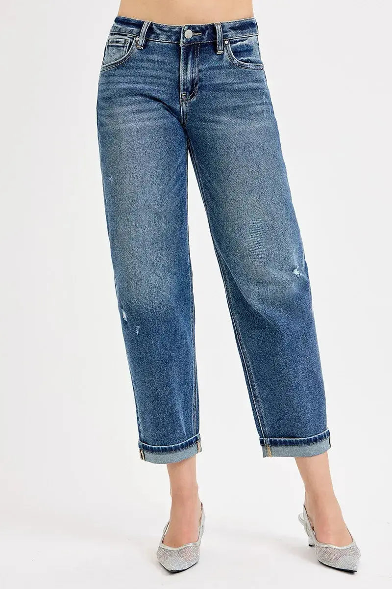 Cropped and cuffed blue jeans worn by a person on a white background.