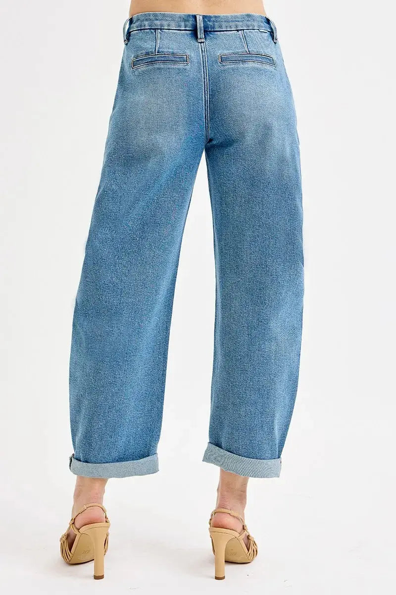 The back of rolled up blue jeans worn by a person on a white background