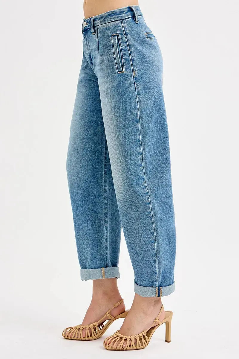 Side view of rolled up light blue jeans worn by a person on a white background