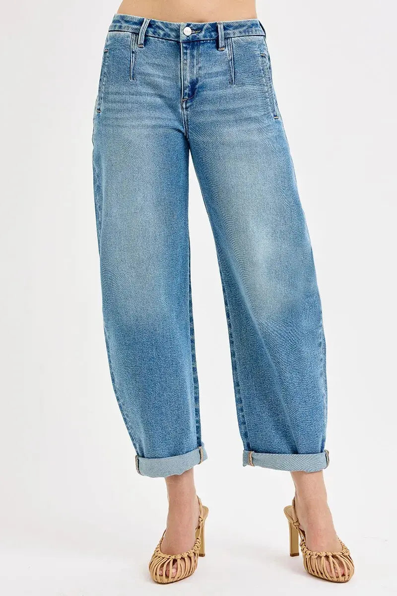 Blue jeans rolled up at the bottom worn by a person on a white background