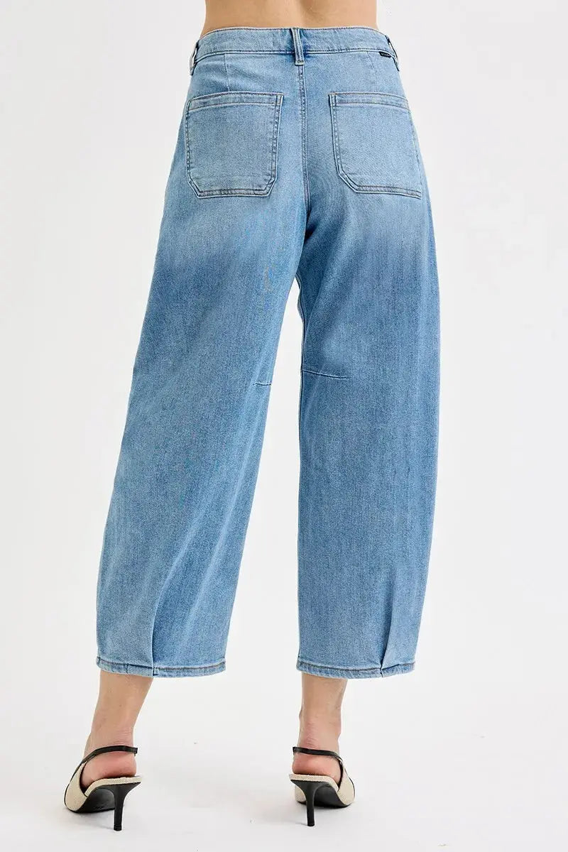 The back view of light blue barrel jeans worn by a person on a white background.
