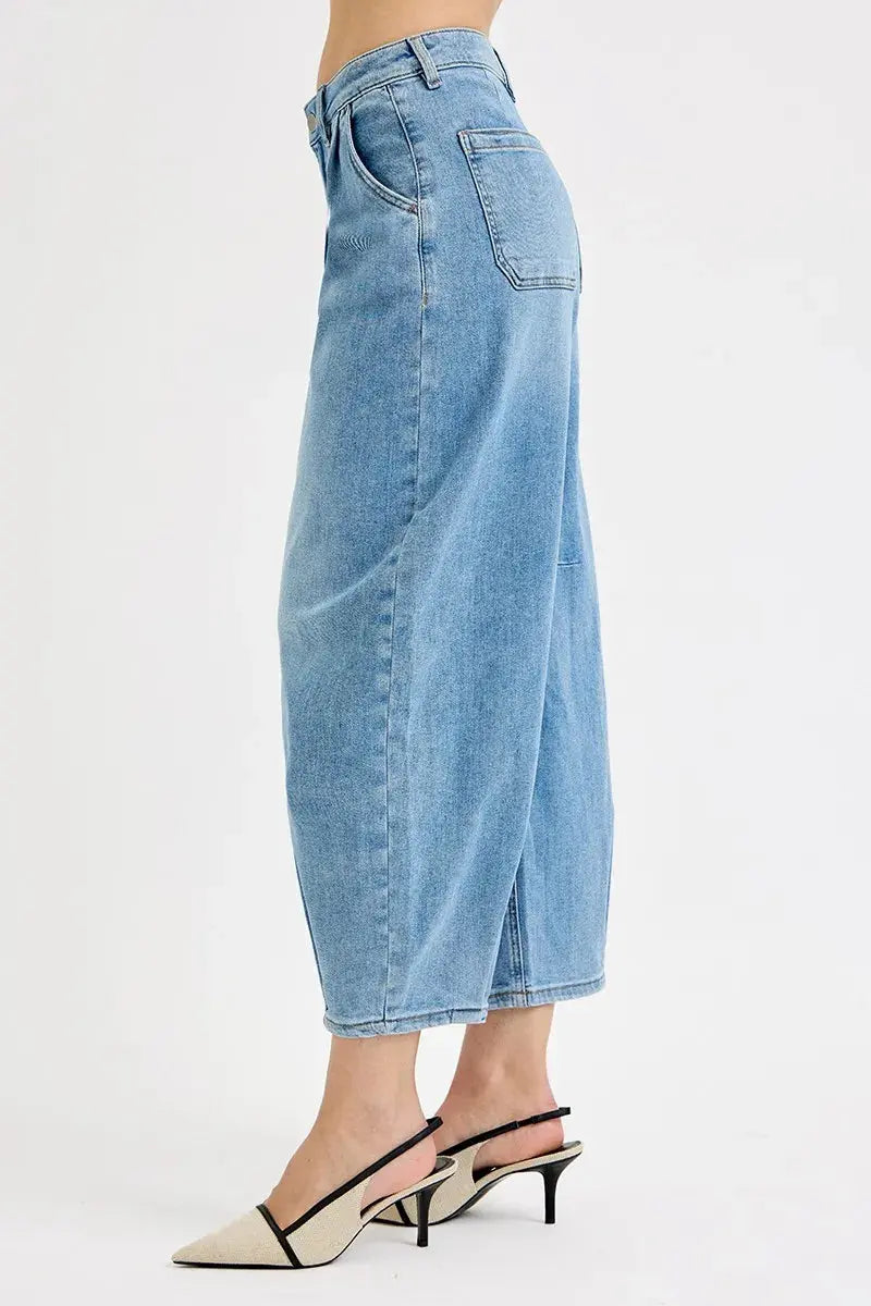 The side view of a person wearing light blue barrel denim jeans.