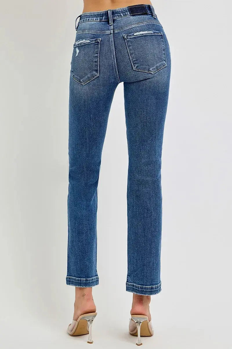 The back view of blue jeans that are cropped and worn by a person on a white background