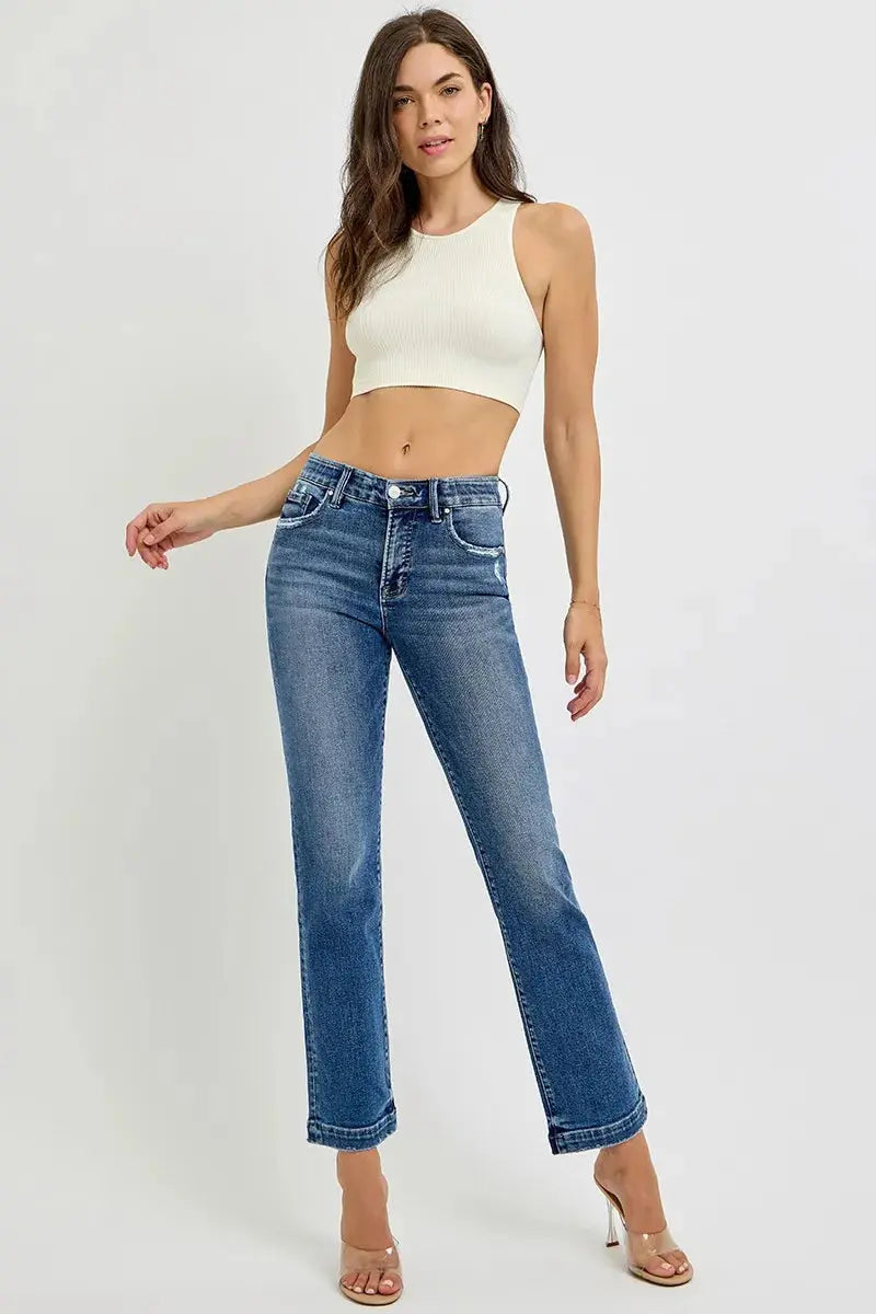 Woman wearing a white crop top and blue jeans on a white background