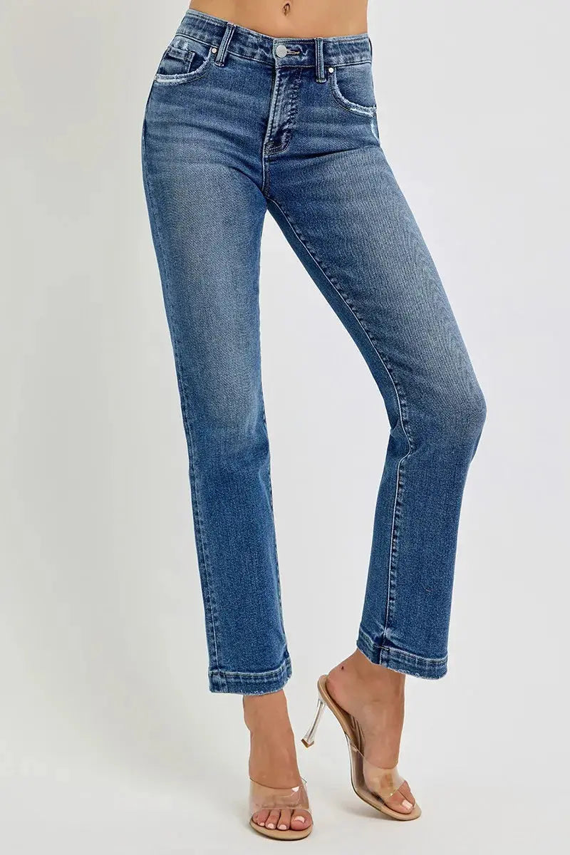 Cropped blue jeans worn by a person in heels on a white background
