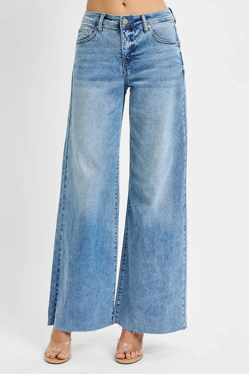 Blue wide leg jeans with raw hem on a white background